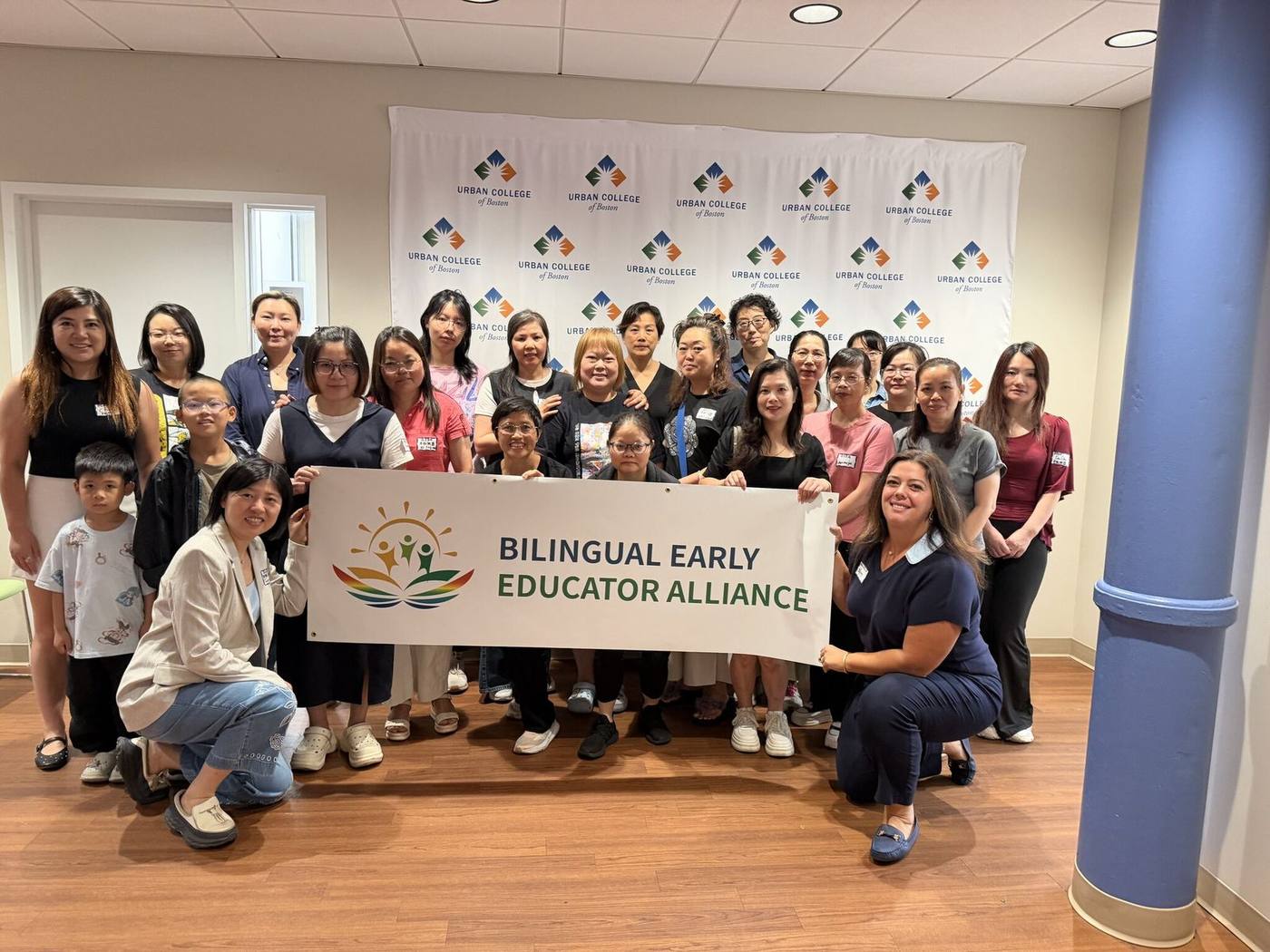 A group of bilingual educators gathered together holding a Bilingual Early Educators Alliance banner